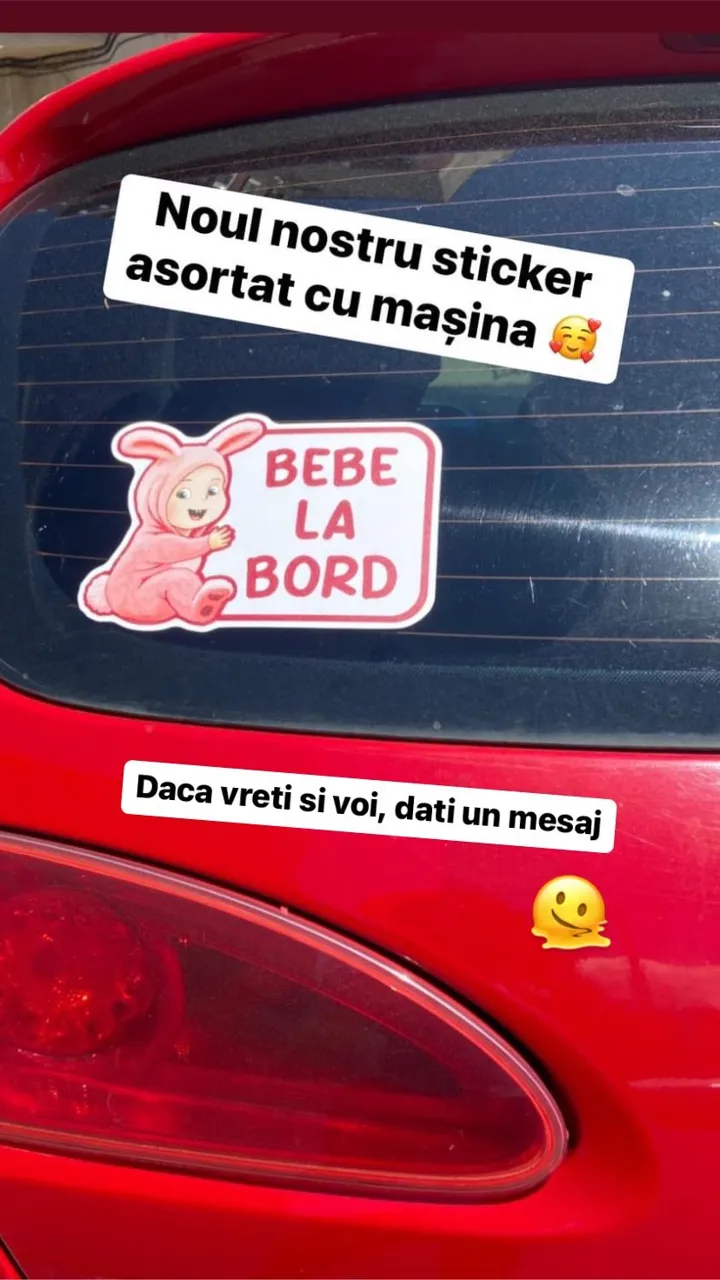 Stickerul Bebe la bord montat pe geamul unei mașini roșii